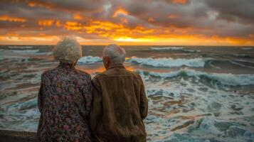 idosos assistindo uma pôr do sol de a oceano foto