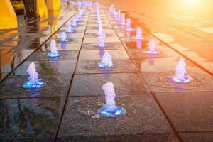 pequeno fontes em a calçada, iluminado de luz solar às pôr do sol ou nascer do sol às horário de verão. foto