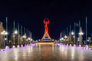 uzbequistão, Tashkent - abril 25, 2023 iluminado monumento do independência dentro a Formato do uma estela com uma humo pássaro dentro a Novo uzbequistão parque às período noturno. foto