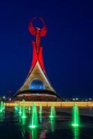 uzbequistão, Tashkent - pode 5, 2023 iluminado monumento do independência dentro a Formato do uma estela com uma humo pássaro, fontes e acenando bandeiras dentro a Novo uzbequistão parque às período noturno. foto