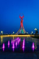 uzbequistão, Tashkent - pode 25, 2023 iluminado monumento do independência dentro a Formato do uma estela com uma humo pássaro e fontes dentro a Novo uzbequistão parque às período noturno. foto