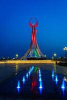 uzbequistão, Tashkent - pode 25, 2023 iluminado monumento do independência dentro a Formato do uma estela com uma humo pássaro e fontes dentro a Novo uzbequistão parque às período noturno. foto