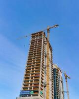 uma guindaste construção uma arranha-céu contra uma azul céu. foto