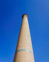 a minarete do uma tijolo mesquita contra uma azul céu. foto