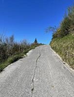 esvaziar asfalto estrada em a camino del norte dentro Espanha conduzindo acima uma Colina em uma ensolarado dia foto