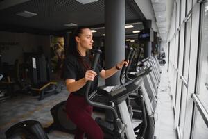 atraente jovem mulher corre em uma esteira, é acionado dentro ginástica esporte clube. foto