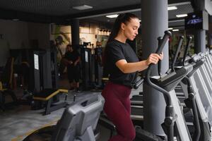 atraente jovem mulher corre em uma esteira, é acionado dentro ginástica esporte clube. foto