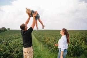 feliz família com pequeno filha gastos Tempo juntos dentro ensolarado campo. foto