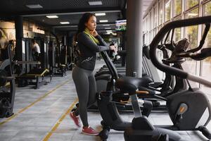 jovem mulher bebendo água e levando uma pausa depois de exercite-se dentro Academia foto