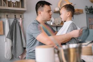 jovem homem e dele filho com forno Folha dentro cozinha. pai com pequeno filho em a cozinha. foto