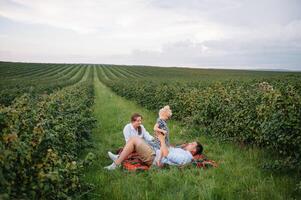 feliz família com pequeno filha gastos Tempo juntos dentro ensolarado campo. foto