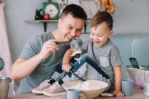 jovem homem e dele filho com forno Folha dentro cozinha. pai com pequeno filho em a cozinha foto