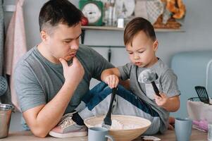 jovem homem e dele filho com forno Folha dentro cozinha. pai com pequeno filho em a cozinha foto