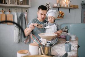 jovem homem e dele filho com forno Folha dentro cozinha. pai com pequeno filho em a cozinha. foto