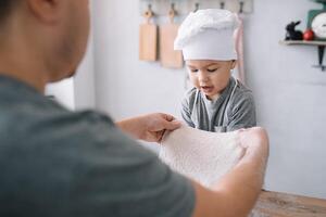 jovem homem e dele filho com forno Folha dentro cozinha. pai com pequeno filho em a cozinha. foto