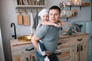 jovem homem e dele filho com forno Folha dentro cozinha. pai com pequeno filho em a cozinha. foto