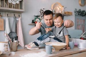 jovem homem e dele filho com forno Folha dentro cozinha. pai com pequeno filho em a cozinha. foto