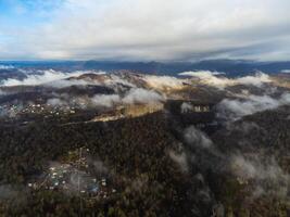 Visão do a outono Vila dentro a montanhas através a nuvens foto