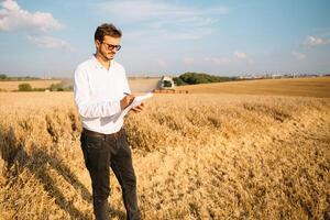 feliz agricultor dentro a campo verificação milho plantas durante uma ensolarado verão dia, agricultura e Comida Produção conceito foto