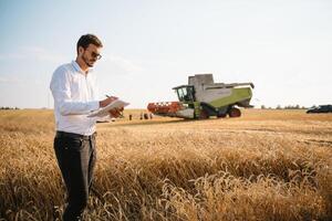 feliz agricultor dentro a campo verificação milho plantas durante uma ensolarado verão dia, agricultura e Comida Produção conceito. foto