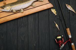 pescaria enfrentar - pescaria fiação, ganchos e iscas em escurecer de madeira fundo. topo Visão foto