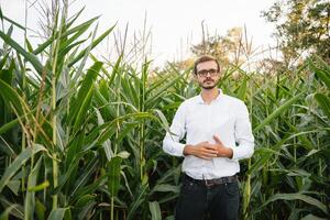 feliz agricultor dentro a campo verificação milho plantas durante uma ensolarado verão dia, agricultura e Comida Produção conceito. foto