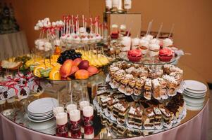 sobremesas com frutas, mousse, biscoitos. diferente tipos do doce pastelaria, pequeno colorida doce bolos, macaron, e de outros sobremesas dentro a doce bufê. doce Barra para aniversário. foto