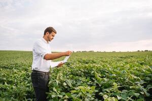 retrato do jovem agricultor em pé dentro soja campo. foto