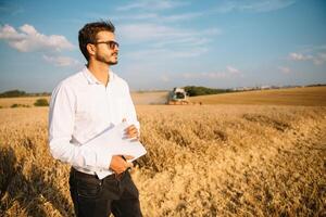 feliz agricultor dentro a campo verificação milho plantas durante uma ensolarado verão dia, agricultura e Comida Produção conceito foto