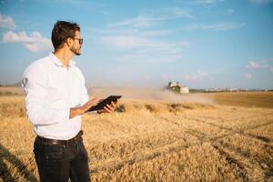 feliz agricultor dentro a campo verificação milho plantas durante uma ensolarado verão dia, agricultura e Comida Produção conceito. foto