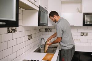 homem corte fresco peixe dentro cozinha dentro lar. homem açougueiro peixe para cozinhar. foto