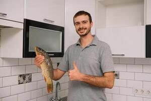 homem corte fresco peixe dentro cozinha dentro lar. homem açougueiro peixe para cozinhar. foto