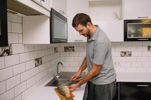 homem corte fresco peixe dentro cozinha dentro lar. homem açougueiro peixe para cozinhar. foto