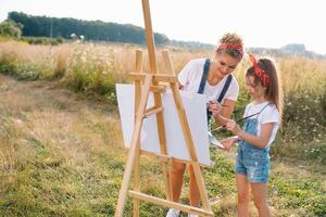 lindo mãe com filha. família dentro uma verão parque. pequeno menina desenho. foto