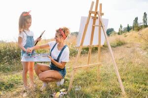 lindo mãe com filha. família dentro uma verão parque. pequeno menina desenho. foto