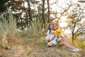 alegre mãe e dela pequeno filha tendo Diversão juntos dentro a verão fundo. feliz família dentro a natureza fundo. fofa meninas com colorida flores foto