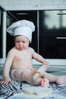 pequeno Garoto sentado em tapete dentro cozinha jogando com cozinhando potes. fofa Garoto cozinhando dentro cozinha às casa foto