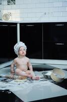 pequeno Garoto sentado em tapete dentro cozinha jogando com cozinhando potes. fofa Garoto cozinhando dentro cozinha às casa foto
