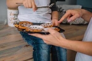 jovem feliz mãe e dela bebê cozinhar biscoitos às casa dentro a cozinha. Natal caseiro Pão de gengibre. fofa Garoto com mãe dentro branco uniforme e chapéu cozinhou chocolate biscoitos foto