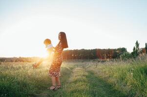 elegante mãe e bonito filho tendo Diversão em a natureza. feliz família conceito. beleza natureza cena com família ao ar livre estilo de vida. feliz família em repouso junto. felicidade dentro família vida. mães dia foto