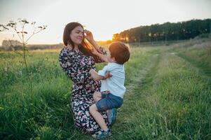 elegante mãe e bonito filho tendo Diversão em a natureza. feliz família conceito. beleza natureza cena com família ao ar livre estilo de vida. feliz família em repouso junto. felicidade dentro família vida. mães dia foto