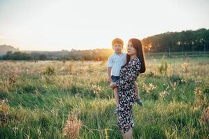 elegante mãe e bonito filho tendo Diversão em a natureza. feliz família conceito. beleza natureza cena com família ao ar livre estilo de vida. feliz família em repouso junto. felicidade dentro família vida. mães dia foto