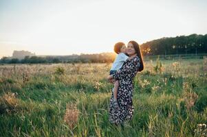 elegante mãe e bonito filho tendo Diversão em a natureza. feliz família conceito. beleza natureza cena com família ao ar livre estilo de vida. feliz família em repouso junto. felicidade dentro família vida. mães dia foto