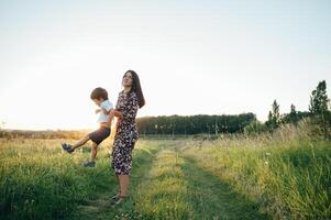 elegante mãe e bonito filho tendo Diversão em a natureza. feliz família conceito. beleza natureza cena com família ao ar livre estilo de vida. feliz família em repouso junto. felicidade dentro família vida. mães dia foto