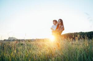 elegante mãe e bonito filho tendo Diversão em a natureza. feliz família conceito. beleza natureza cena com família ao ar livre estilo de vida. feliz família em repouso junto. felicidade dentro família vida. mães dia foto