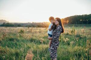 elegante mãe e bonito filho tendo Diversão em a natureza. feliz família conceito. beleza natureza cena com família ao ar livre estilo de vida. feliz família em repouso junto. felicidade dentro família vida. mães dia foto