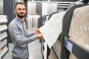 masculino construtor escolhendo papeis de parede dentro hardware loja foto