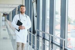 jovem masculino médico dentro uma corredor do uma geral hospital foto