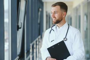 retrato do bonito jovem médico em hospital corredor foto