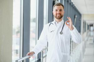 retrato do uma masculino médico em pé dentro uma hospital corredor. foto